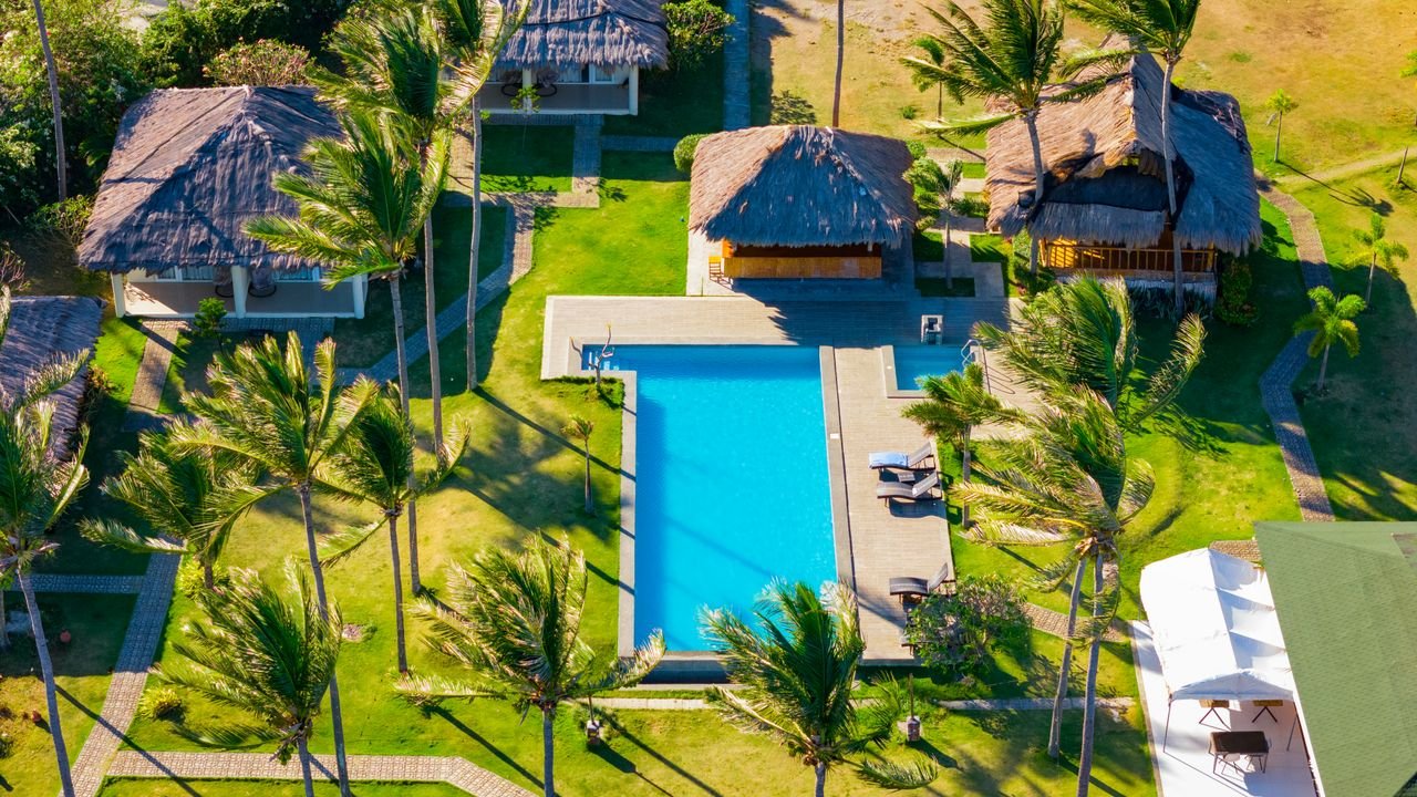 Mastering the First Impression: Your intriguing post title goes here Stunning aerial view of a tropical resort with a pool, lush greenery, and palm trees in Bacong, Philippines.